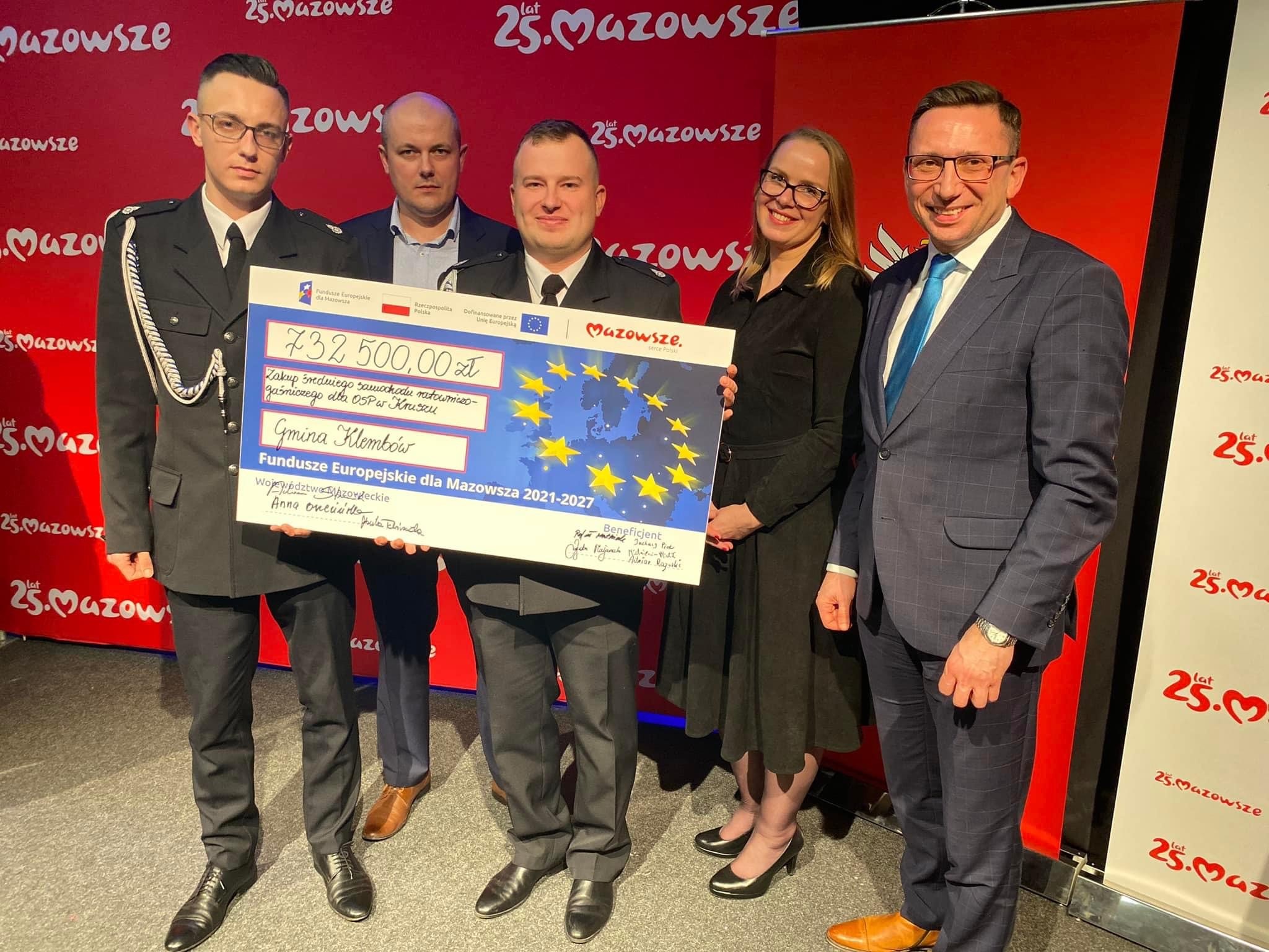 Zdjecie os&oacute;b uczestniczących w oficjalnym przekazaniu symbolicznego vouchera na zakup wozu