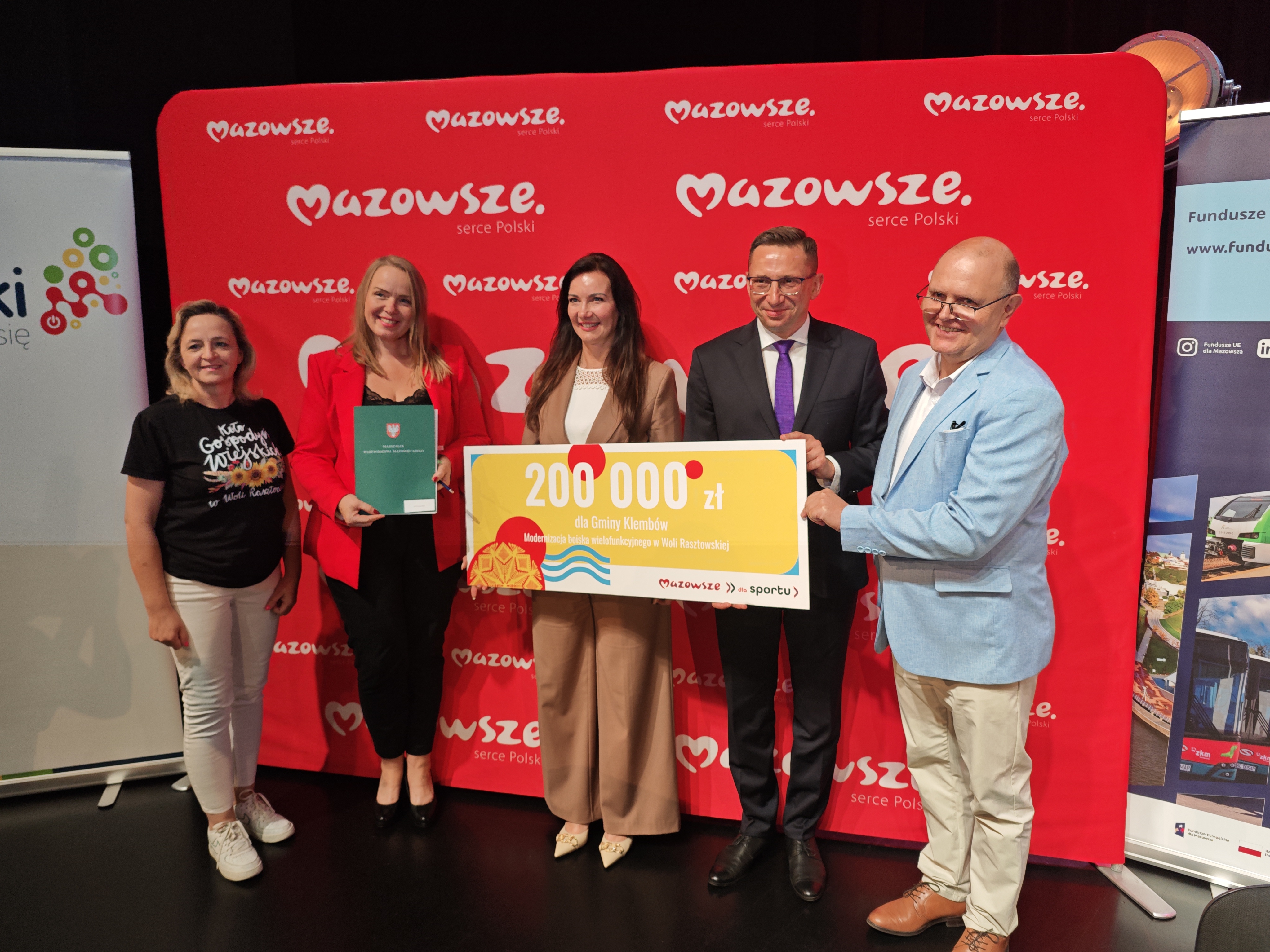 Moment wręczenia symblicznego czeku z dofinansowaniem na remont boiska w Woli Rasztowskiej